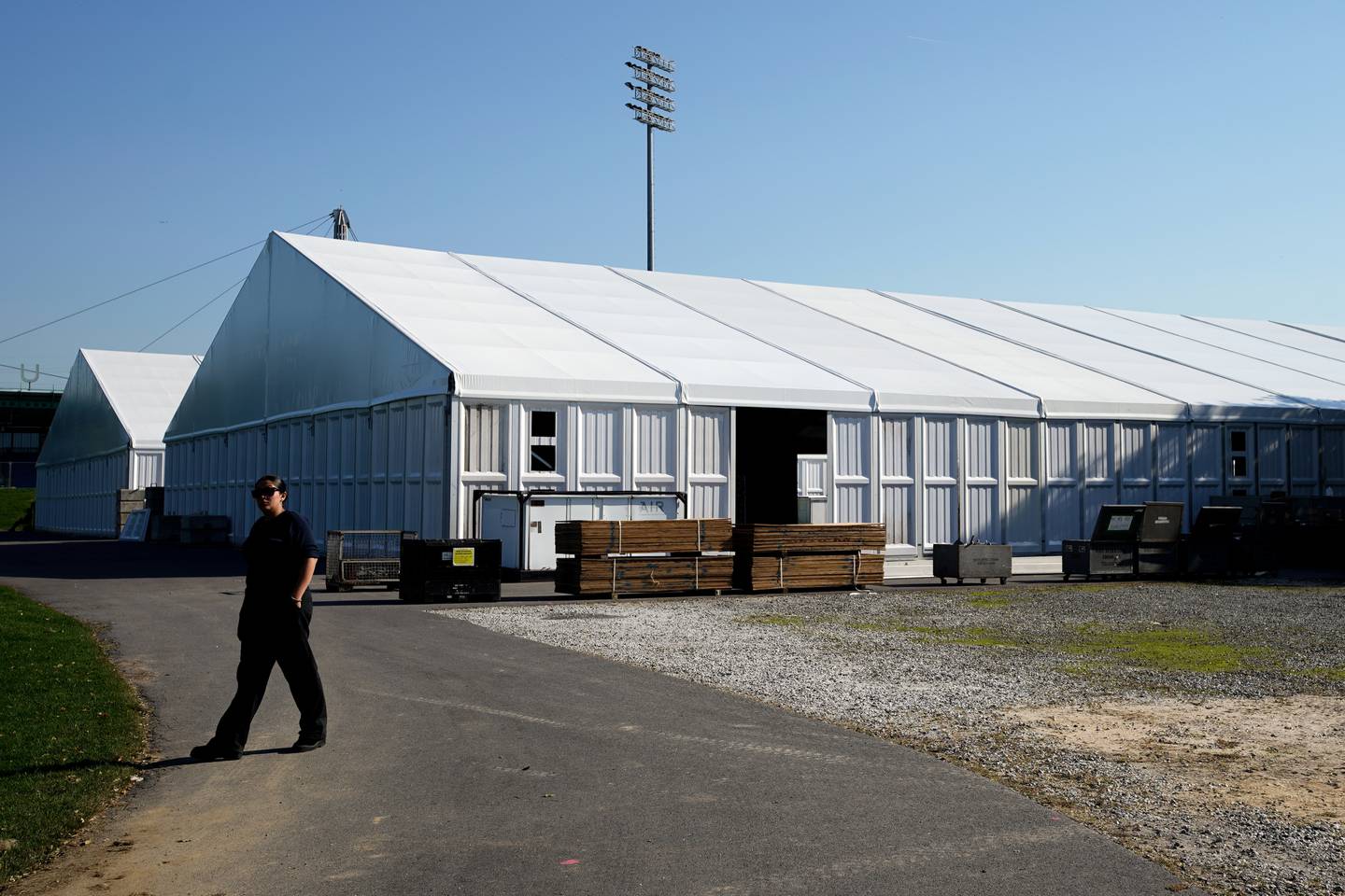 Workers gather tents the size of hangars, Tuesday, October 11, 2022, on Randalls Island, New York. 